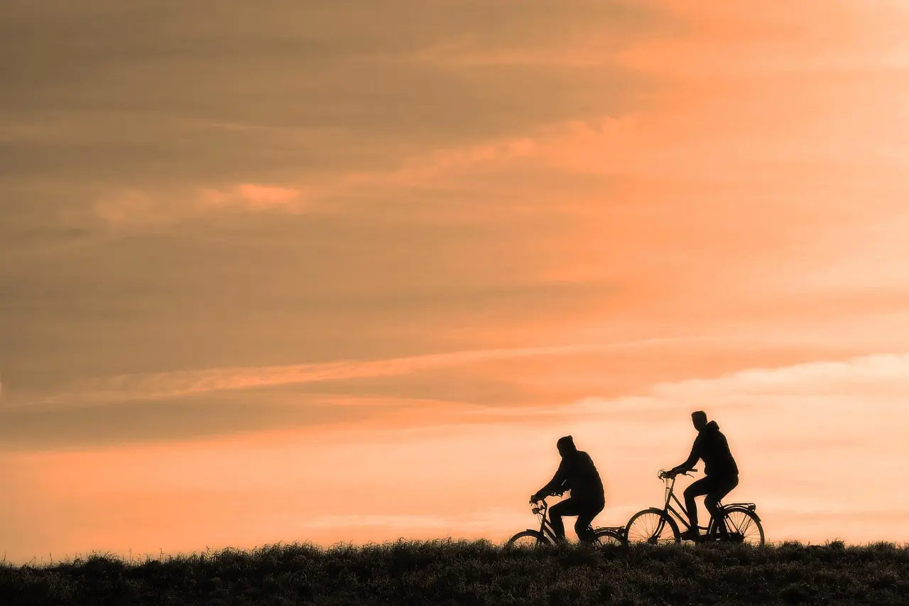 To cyklister i silhuet mod en orange himmel